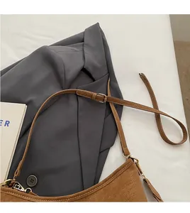 Detail of adjustable long shoulder strap and smooth matte finish on brown tote bag