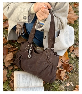 Close-up of brown suede tote bag with star pendant on a cozy autumn leaf background