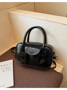 Detail of glossy black patent leather bowling bag with silver metal buckles and strap