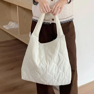 Close-up of white quilted nylon tote bag with wavy texture and metal snap button closure