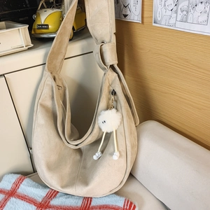 Détail du sac demi-lune en daim beige orné d'un joli pendentif en peluche blanche