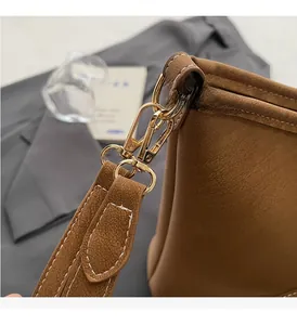 Macro detail of brown lychee leather bag with gold hardware and white stitching