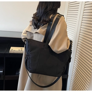 Minimalist black nylon tote bag with side drawstring pocket and adjustable shoulder strap