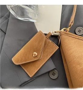 Close-up of brown textured mini coin purse with gold clasp and white contrast stitching