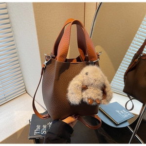 Detailed view of brown and orange leather bucket bag with cute plush rabbit charm