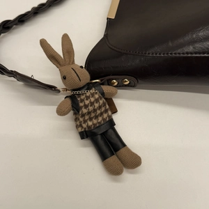 Detail of a brown knit rabbit charm with houndstooth outfit hanging on a brown leather bag