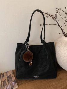Black large capacity shoulder tote bag in matte leather with a brown pom-pom charm decoration