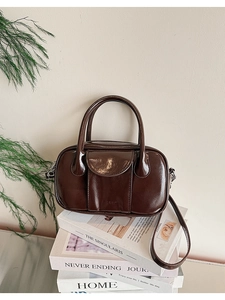 Detail of dark brown oil wax leather bowling bag with LIUUU logo on white books
