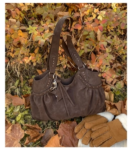 Detail of dark brown suede tote bag with star pendant and rivets in autumn setting