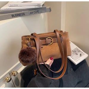 Detail showing brown leatherette handbag with belt buckle and dark brown pompom accessory