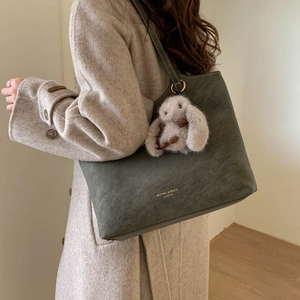 Olive green large tote bag detail with matte leather texture and plush rabbit charm