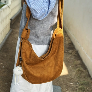 Détail du sac hobo en similicuir suédé marron mat avec un pompon en peluche blanche