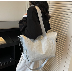 Detail view of large canvas tote bag with side pocket and wide strap on model