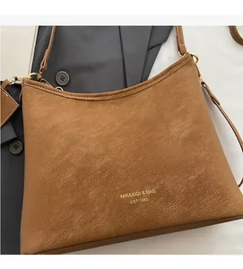 Close-up of caramel brown leather shoulder bag featuring gold logo and grainy texture