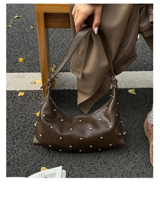 Detail of dark brown hobo bag featuring silver rivets and adjustable strap in autumn setting
