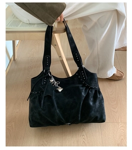 Close-up of black suede tote bag featuring silver studs and Y2K star chain charms