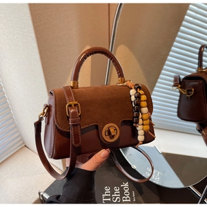 Detail of vintage brown leather handbag with suede flap and colorful beaded charm