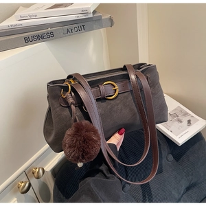 Close-up of vintage tote bag with gold buckle, brown straps and plush ball charm detail