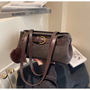 Close-up of vintage matte shoulder bag with gold ring buckle and soft plush pompom