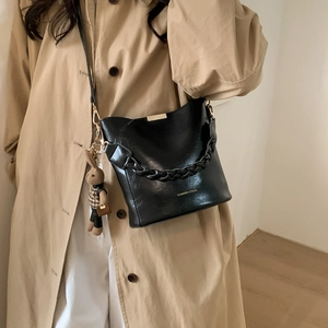 Detail view of black bucket bag with woven handle and cute rabbit pendant charm