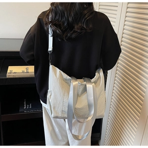 Detailed view of white oversized canvas tote bag with adjustable strap worn by model