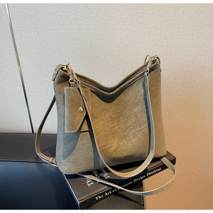 Olive green hobo shoulder bag with detachable mini pouch on a minimalist art book
