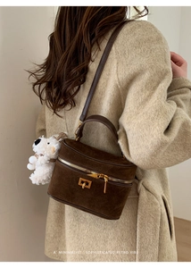 Détail d'un sac boîte en daim marron avec boucle dorée et porte-clés ours blanc mignon