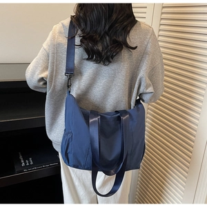 Blue high-capacity tote bag shown as a crossbody pack on back in a library lifestyle setting