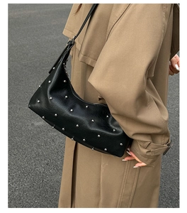 Detail of a black leather shoulder bag featuring silver rivets and a punk style design