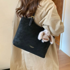 Detail of black matte leather tote bag featuring elegant text and a cute bunny pendant