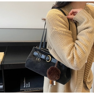 Detail of black vintage shoulder bag featuring gold buckle and brown faux fur charm