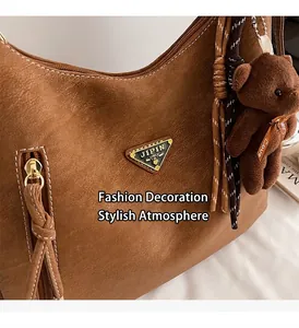 Detail of brown litchi texture leather bag with metal plate and plush bear charm