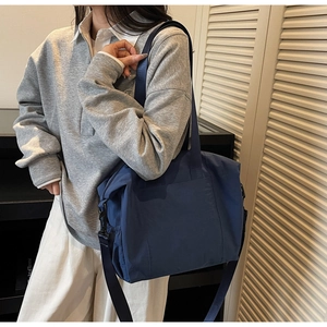 Detail of a large capacity navy nylon tote bag with adjustable straps on a model