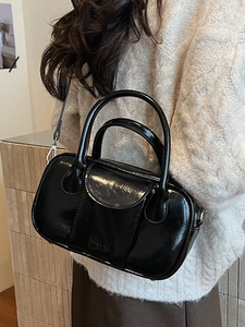 Glossy black bowling bag with top handles and shoulder strap shown on model's back