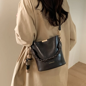Close-up of black PU leather bucket bag with woven handle and cute rabbit charm
