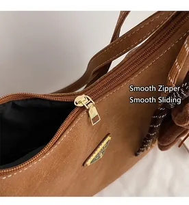 Close-up of smooth gold-tone zipper and triangular logo on brown leather tote bag