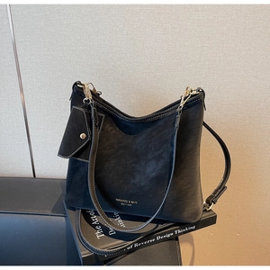 Close-up of black hobo bag with white contrast stitching and a small coin purse charm