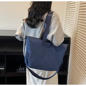 Detail of navy blue nylon tote bag showing side pleated pockets and adjustable strap