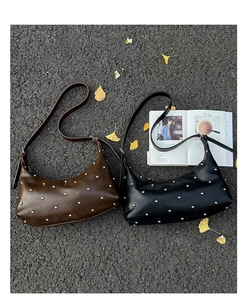 Close-up of crescent-shaped leather bags with silver rivets and Ginkgo leaves background