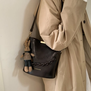 Detail of vintage bucket bag with woven chain and cute bunny pendant on model