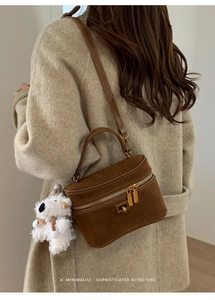 Détail d'un sac boîte en daim marron foncé avec zip doré et charm ours en peluche