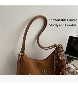 Detail of brown vintage tote bag with triangular metal logo and plush bear charm