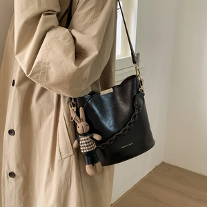 Detail of black bucket bag with gold hardware and a cute brown rabbit plush charm