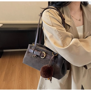 Detail of vintage brown suede shoulder bag with decorative metal ring and plush ball pendant