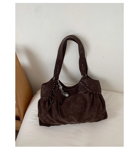 Close-up of brown suede tote bag featuring silver studs and a star leather charm