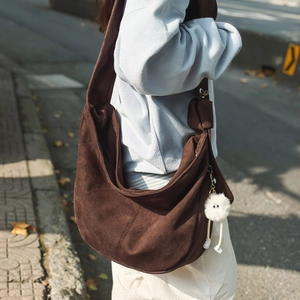 Sac hobo marron en daim synthétique avec une peluche blanche sur la sangle