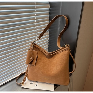 Detail view of brown matte tote bag with gold lettering and small hanging pouch accessory