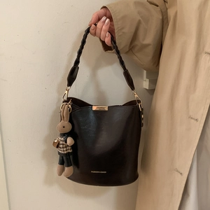 Detail of dark brown leather bucket bag with fashion logo and a small rabbit charm
