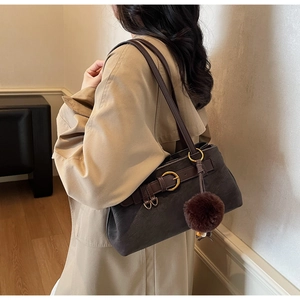 Detailed macro view of dark vintage leather handbag with golden rings and plush charm