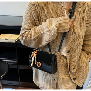 Detail of vintage black crossbody bag with matte leather finish and decorative wood beads